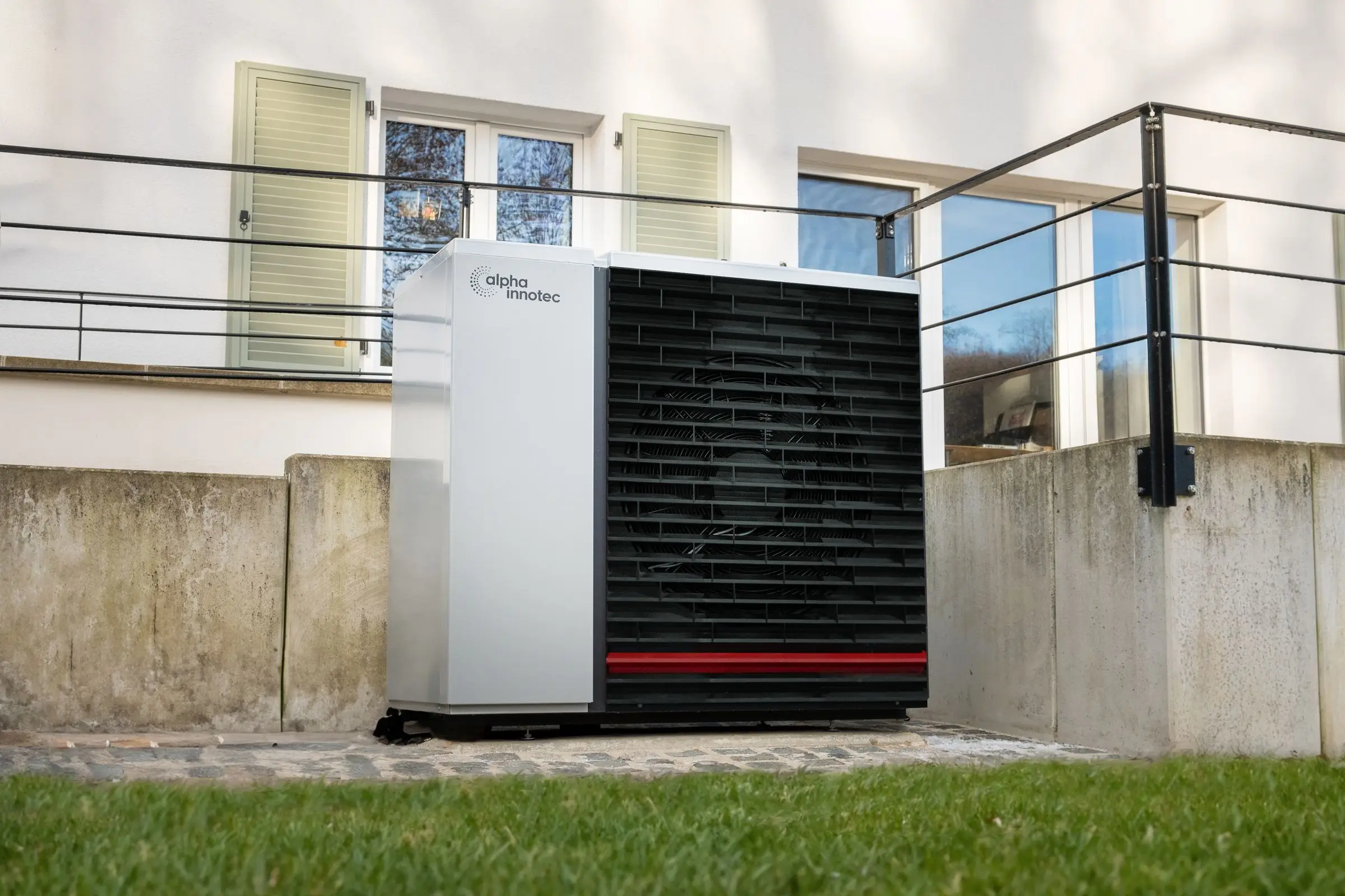 Wärmepumpe an einem Wohnhaus mit Holzfassade