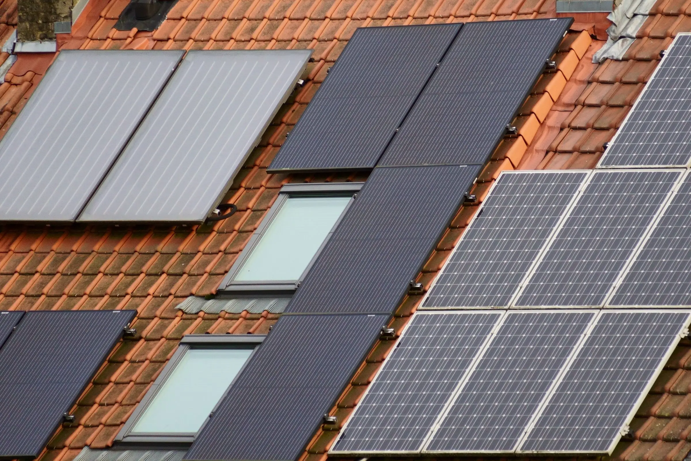 PV-Module auf einem roten Ziegeldach mit Dachfenstern